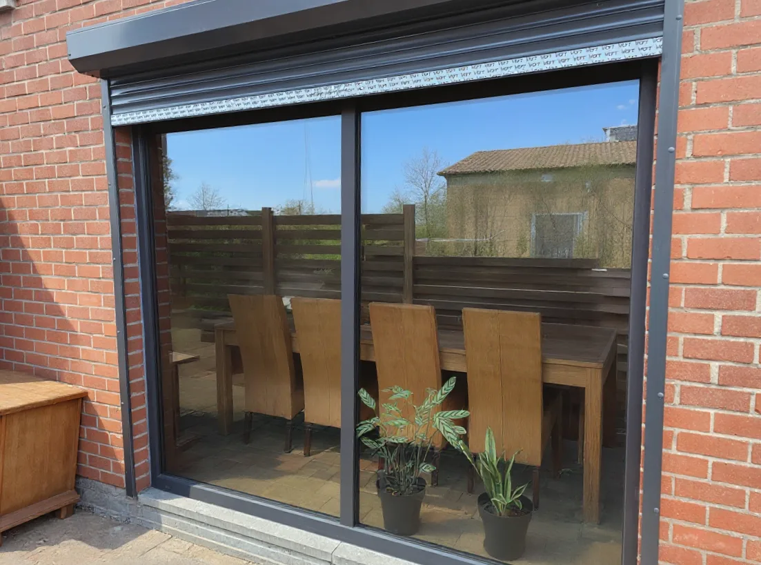 Large porte coulissante et volet roulant menant à la terrasse du jardin