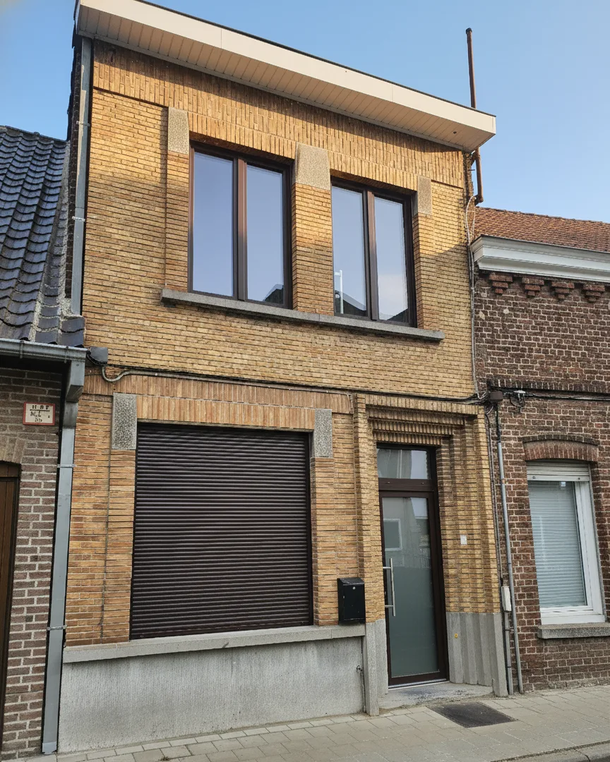 Antwerps geelbakstenen rijtjeshuis met donkerbruine ramen en rolluik